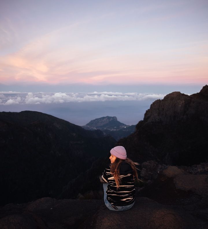 Rückansicht einer Wanderin bei einer Wanderpause auf einem Berggipfel, die den Blick in die Weite genießt – Sinnbild für mentale Klarheit